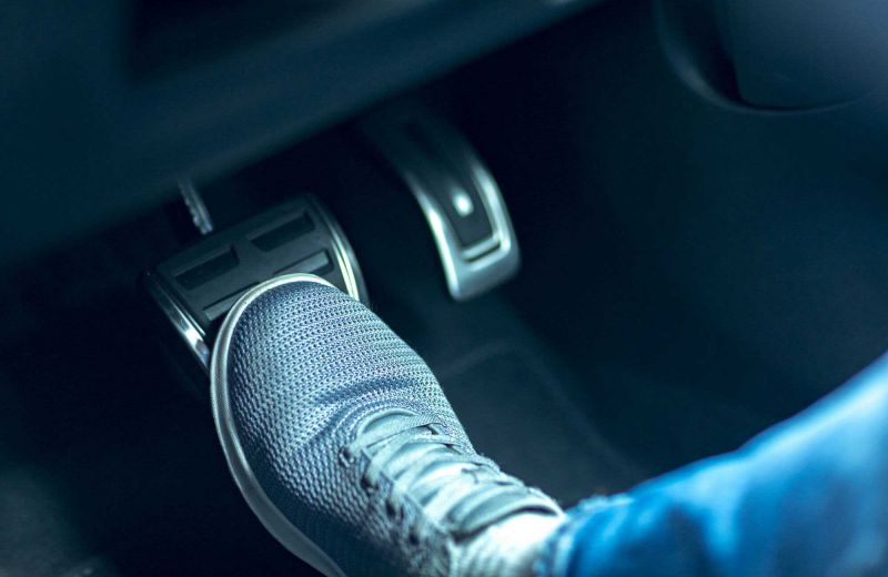Fuß steht auf dem Bremspedal eines Autos.
