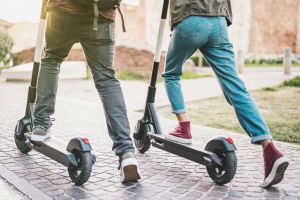 Zwei Männer steigen auf ihren E-Scooter.
