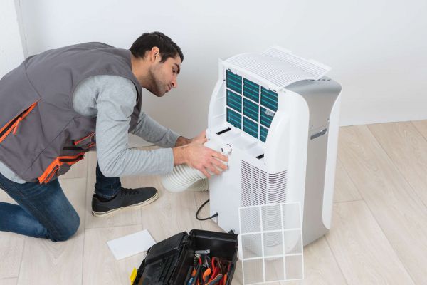 Mann befestigt Abluftschlauch an mobiler Klimaanlage.