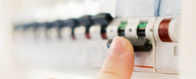 Mann schaltet Sicherung an einem Sicherungskasten aus