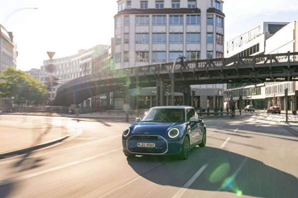 Mini Cooper SE fährt auf der Straße in einer Stadt.