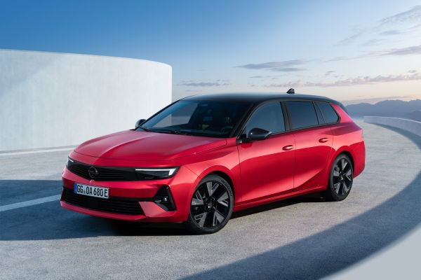 Der Opel Astra Sports Tourer Electric in rot fährt entlang einer weißen Wand.
