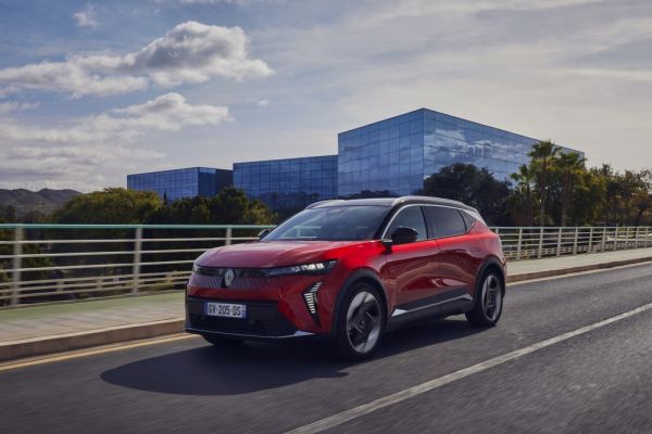 Roter Renault Scénic E-Tech fährt eine Straße entlang