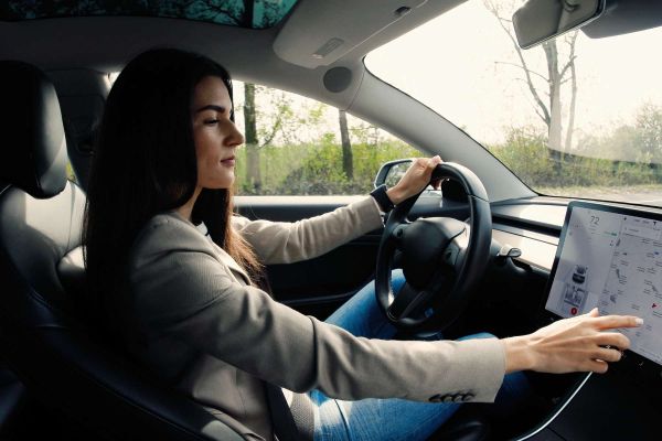 Frau sitzt im Auto und sucht nach einer Ladesäule für ihr E-Auto.