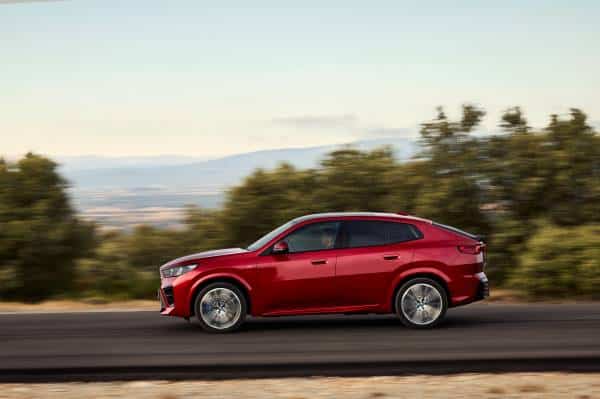 Roter BMW iX2 während der Fahrt von der Seite.