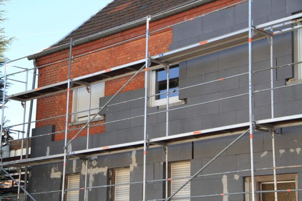 Haus mit Baugerüst während Dämmarbeiten