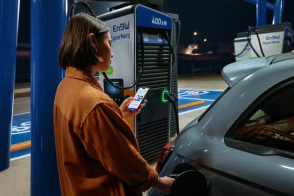 Frau lädt ihr E-Auto am EnBW Ladepark mit der EnBW mobility+ App