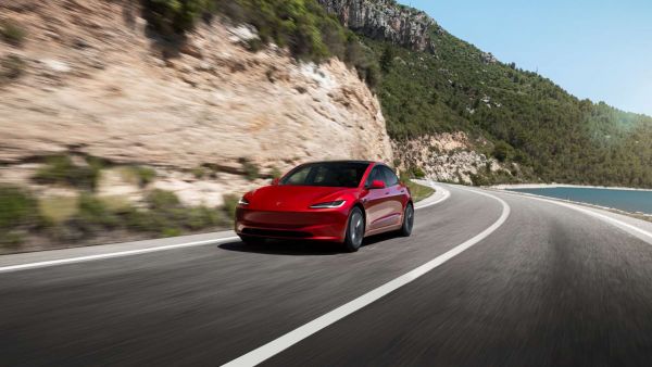 Der rote Tesla Model 3 auf einer Gebirgsstraße. 