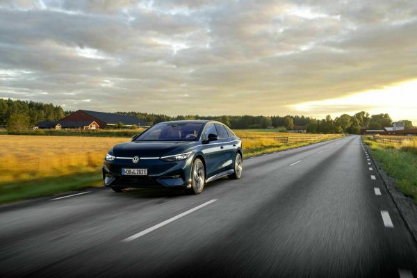 Der VW ID.7 fährt an einem gelben Rapsfeld vorbei.