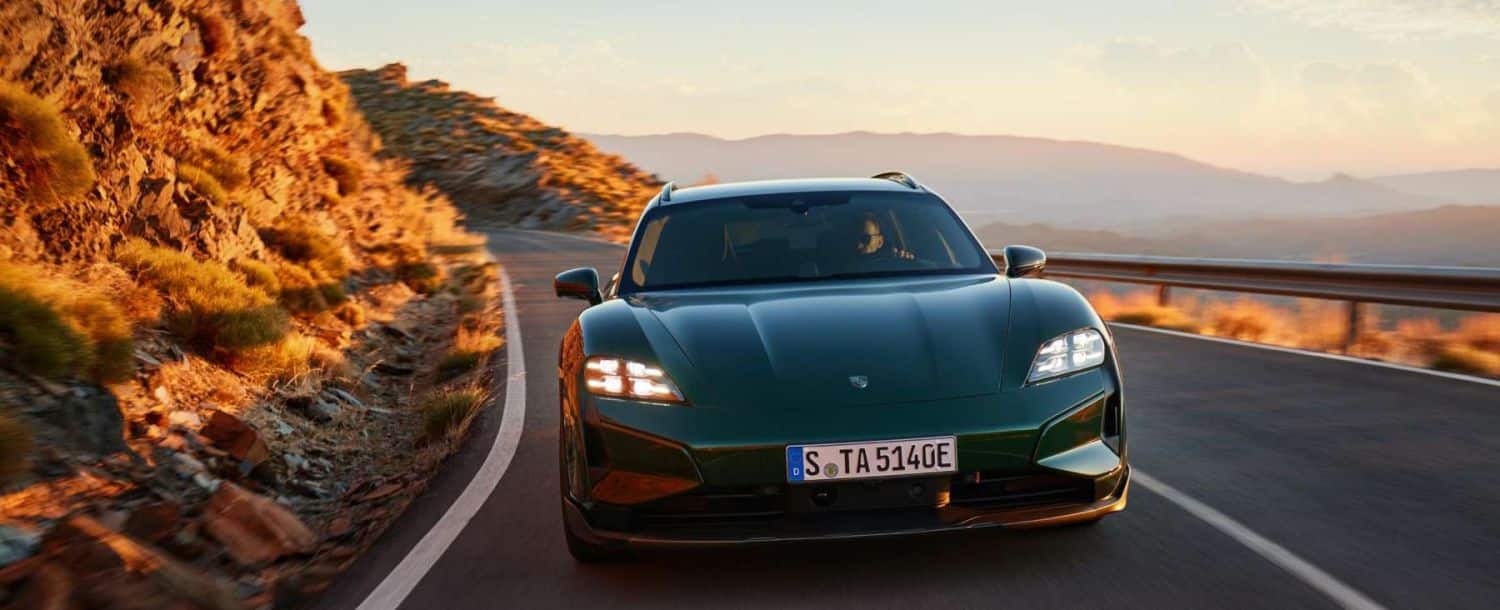 Ein grüner Porsche Taycan fährt an der Küste entlang.