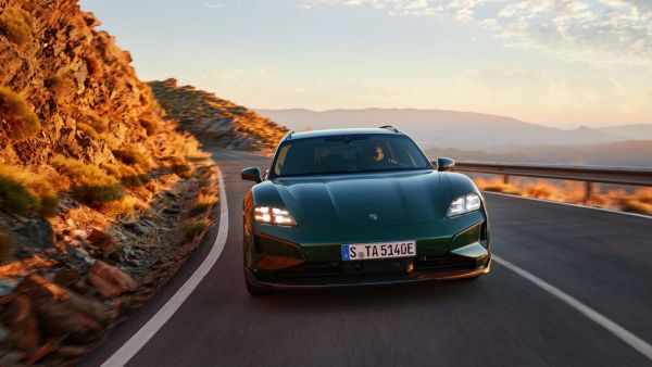 Ein grüner Porsche Taycan fährt an der Küste entlang.