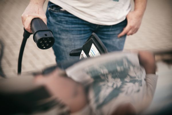 Eine Person am Laden des E-Autos.