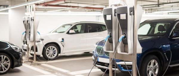 Zwei Autos laden an einer Wallbox in einer Garage.