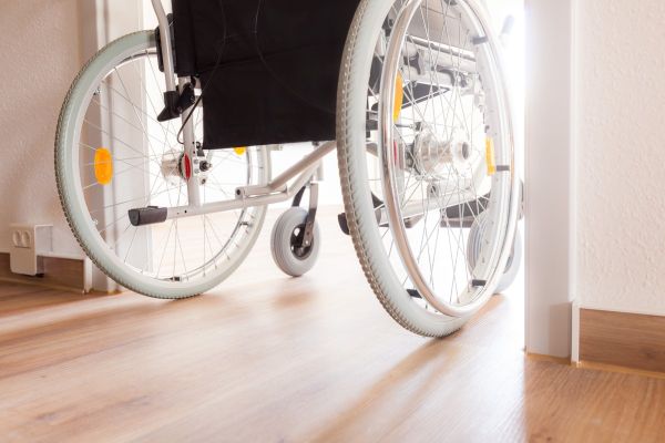 Rollstuhl fährt in einem Wohnraum durch eine breite Tür