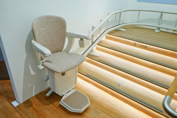 Treppenlift in einem Hausflur mit beleuchteter Treppe